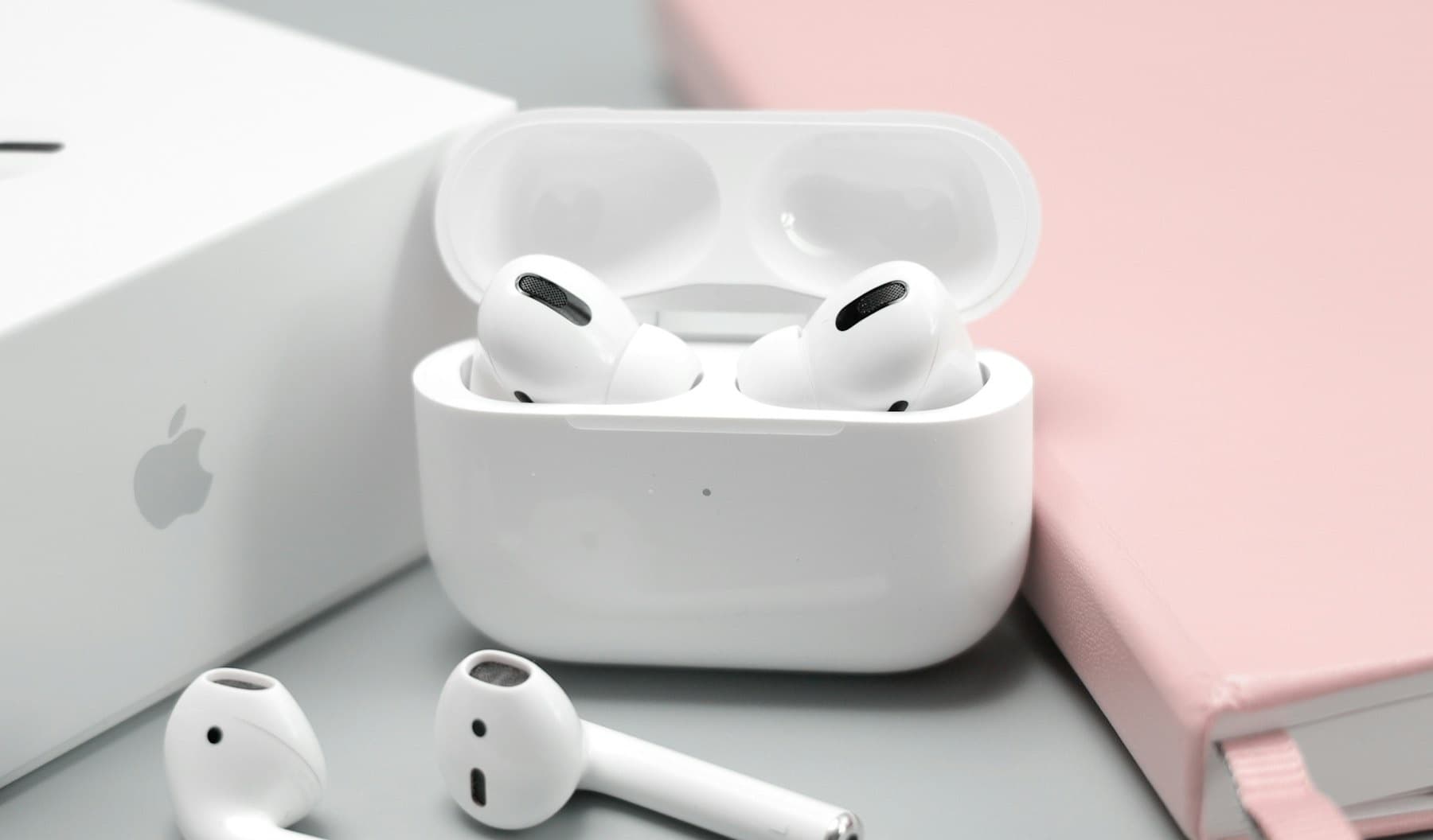A pair of AirPods Pro in their open charging case, next to a pair of original AirPods