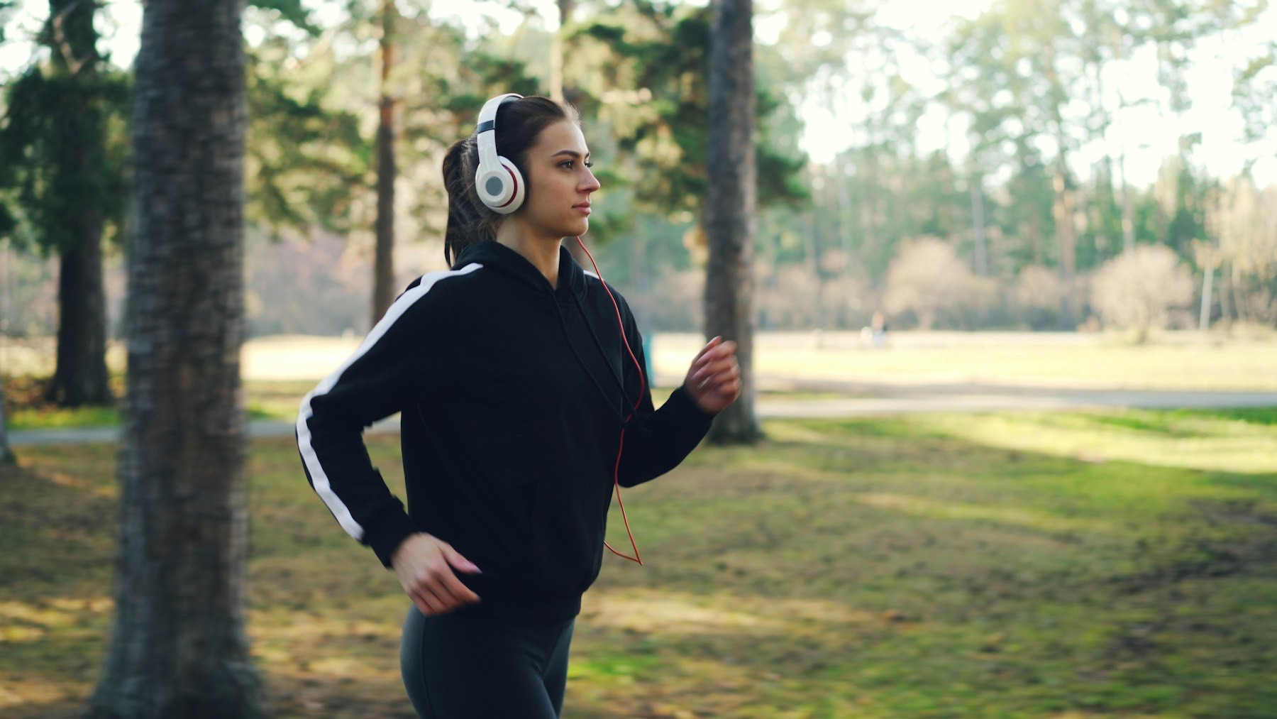 A woman jogging in a park, wearing headphones