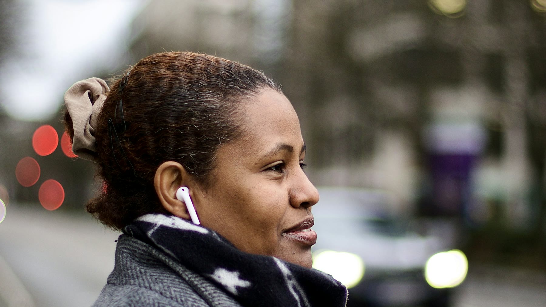 A woman on a city street with a white AirPod in her ear
